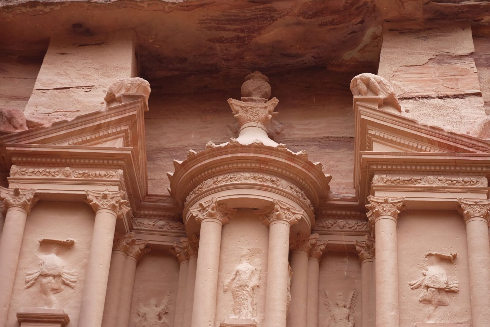 Close-up view of the carved façade of Al Khazna (the Treasury) in Petra, showing columns and sculpted details in rose-coloured sandstone.