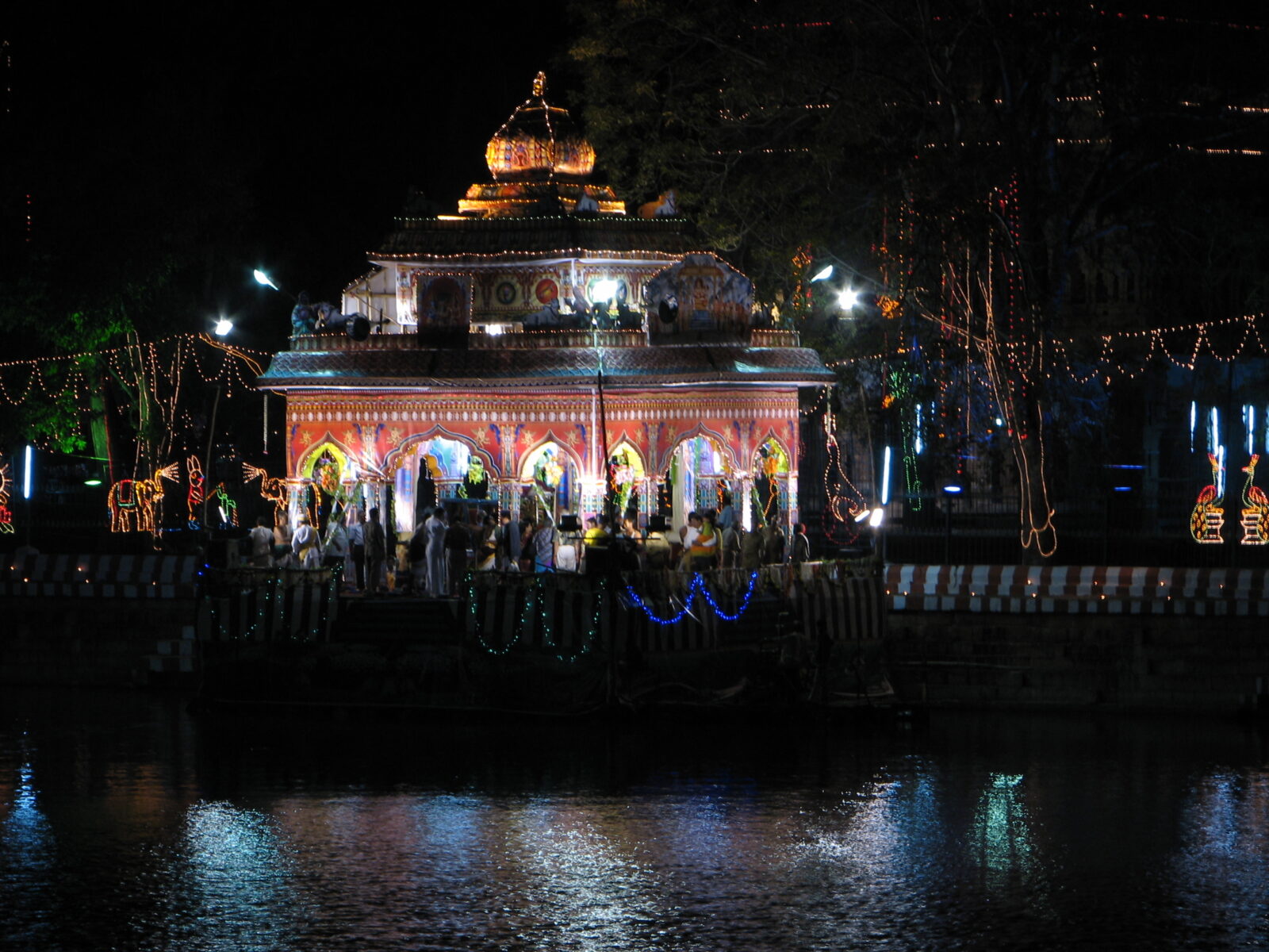 Illuminated temple float during the Madurai Theppam festival reflected in the water at night