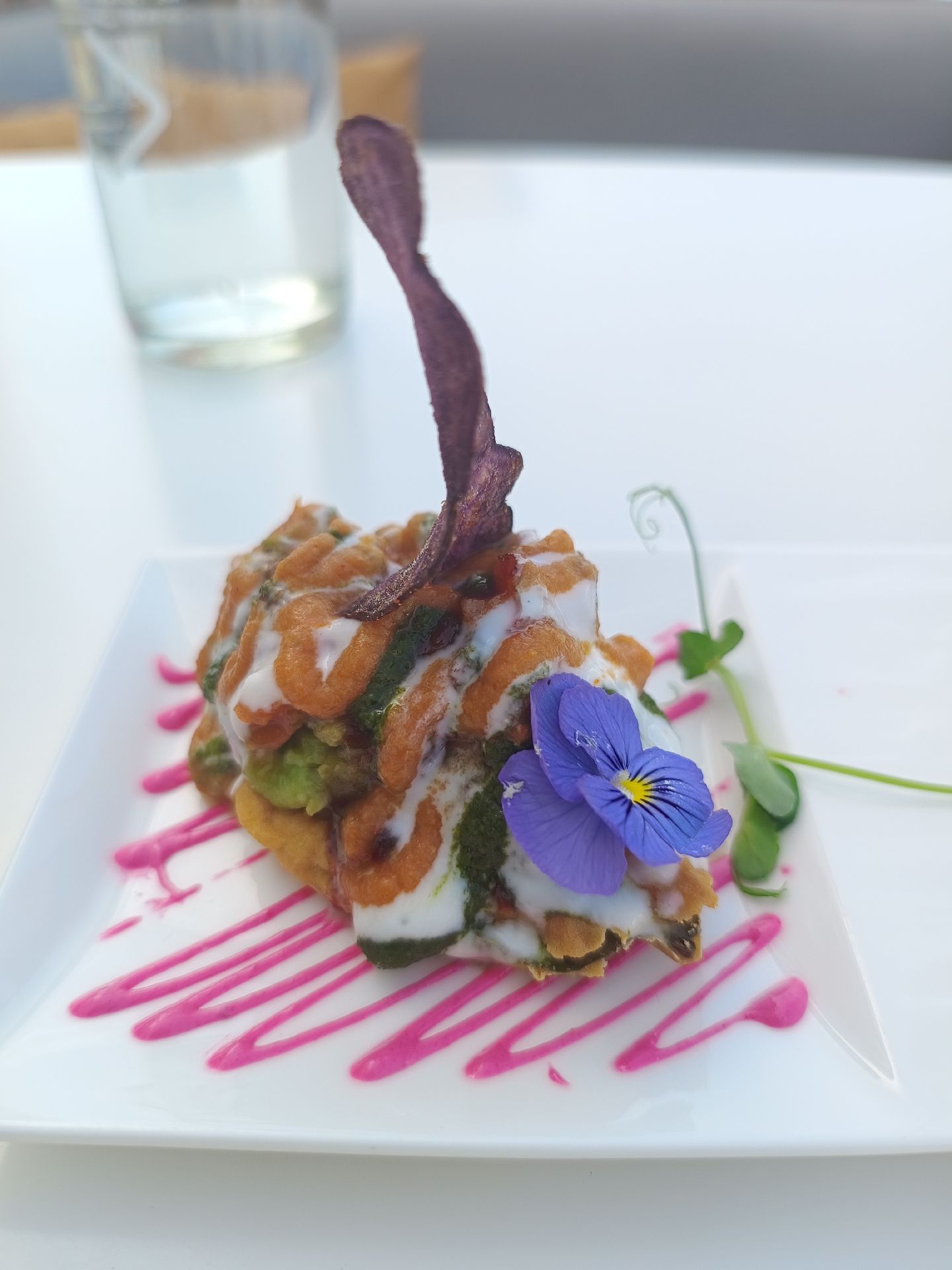 Sculptural Indian appetiser with yoghurt, chutneys and edible flower garnish